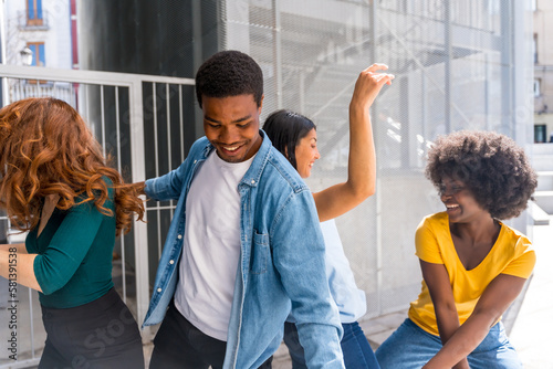 Multiethnic young friends dancing in the city, group of happy people having fun together