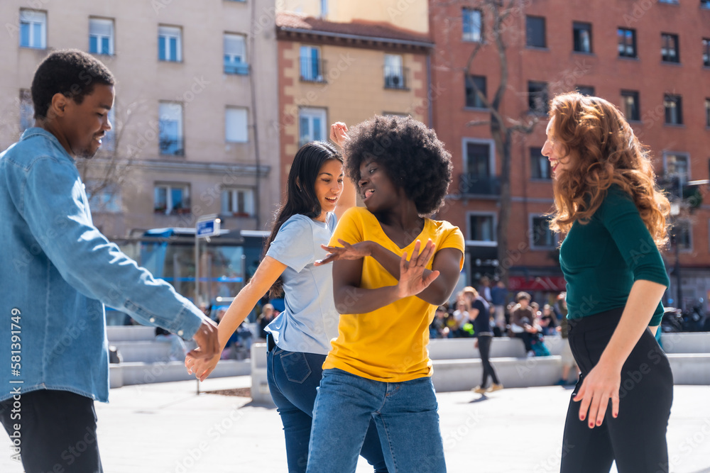 Multi ethnic young friends dancing and smiling a city square, group of happy people having fun together