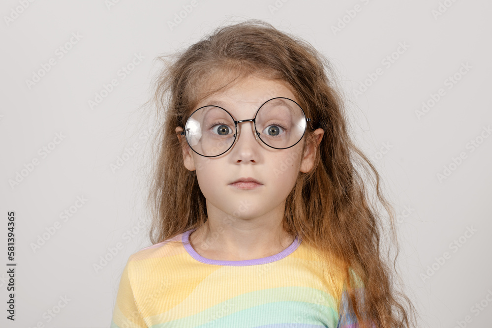 Fototapeta premium Portrait of a surprised little smart girl in glasses. Isolated on white background.