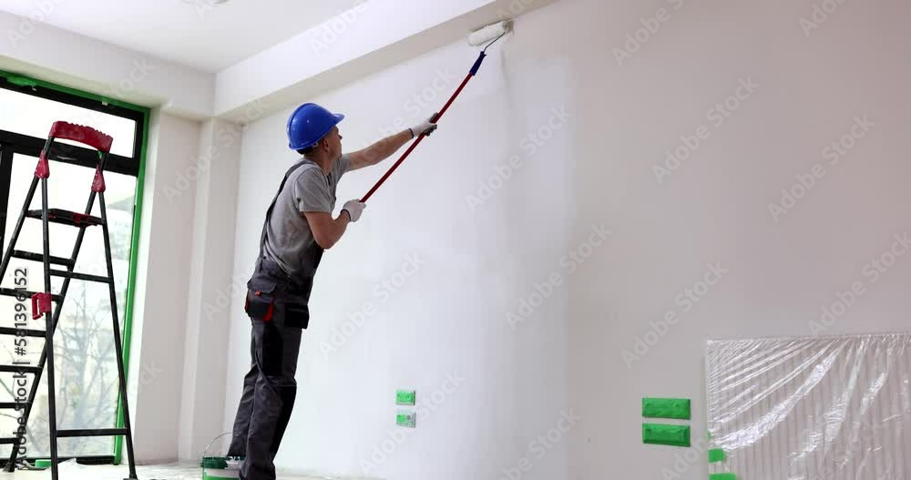 Painter painting wall with roller at construction site