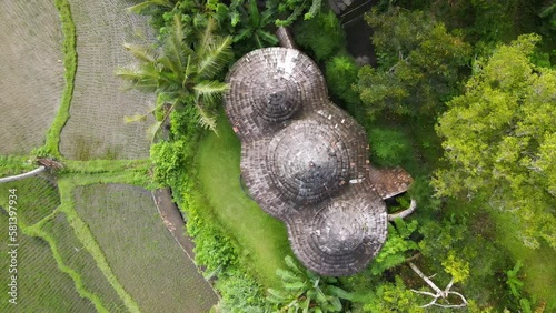 Drone top-down view above the roof of a Balinese villa in the middle of a rice field in Kecamatan Selat Bali, steady shot photo