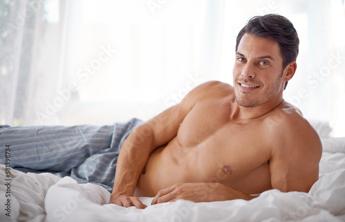 Sexy, smile and portrait of a man on a bed for relaxing, comfort and rest in pyjamas. Comfy, cozy and handsome young man content in the bedroom, smiling and confident to relax on the weekend