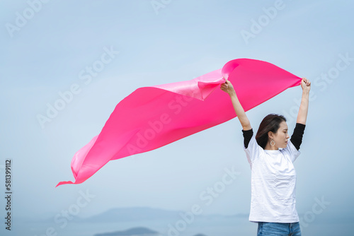 青空の中でピンクの布を持った女性