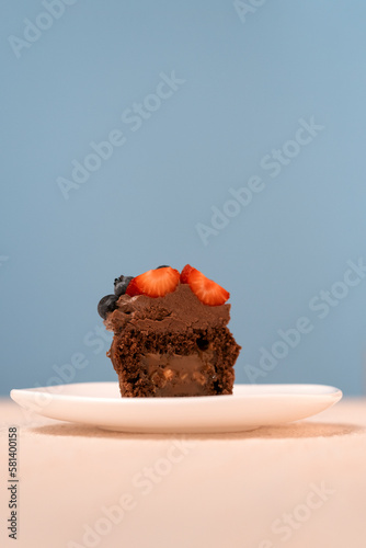 Chocolate cupcakes with berriers and chocolate frosting on white plate. Blue background. Fresh muffin. Vertical frame. photo