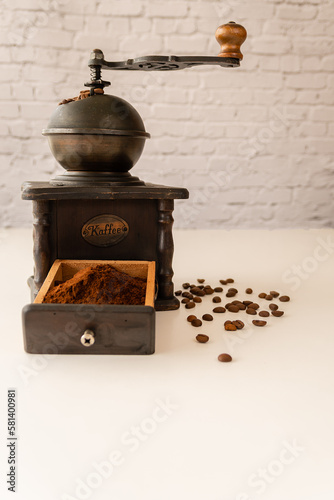 antique manual coffee grinder with roasted and ground coffee beans. vertical photograph. White background and copy space