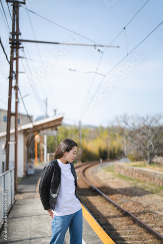ローカル線の無人駅にいる女性 © peach100