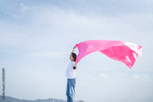 青空とピンクの布を持った女性
