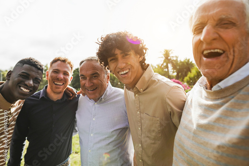 Multi generational men smiling in front of camera - Male multiracial group having fun togheter outdoor - Focus on rught boy face photo