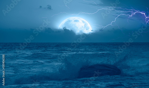 Night sky with full moon and lightning in the clouds on the fore ground strong sea wave 