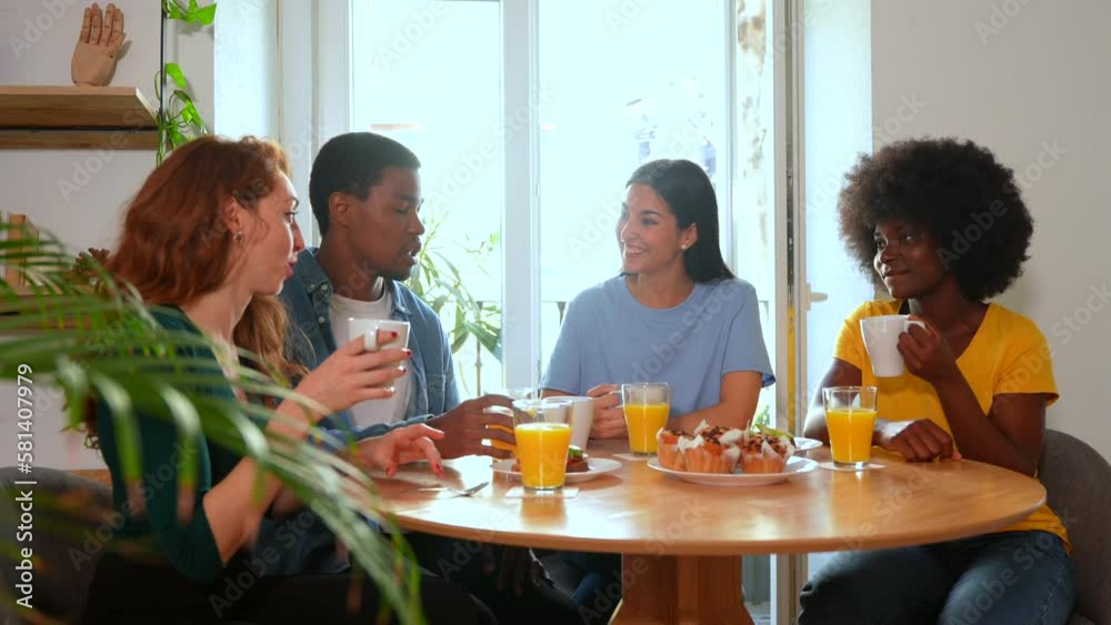 Smiling multiethnic friends over breakfast with orange juice and muffins at home Smiling multiethnic friends over breakfast with orange juice and muffins at home