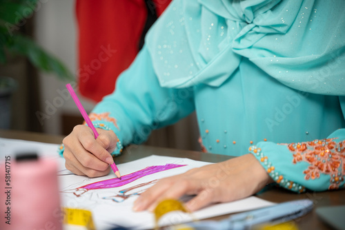 Islam woman in design home sitting at desk sketching fashion design.