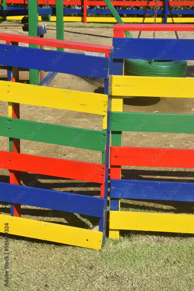 Primary Color Blue, Yellow, Green, and Red Wooden Fence  around a Playground