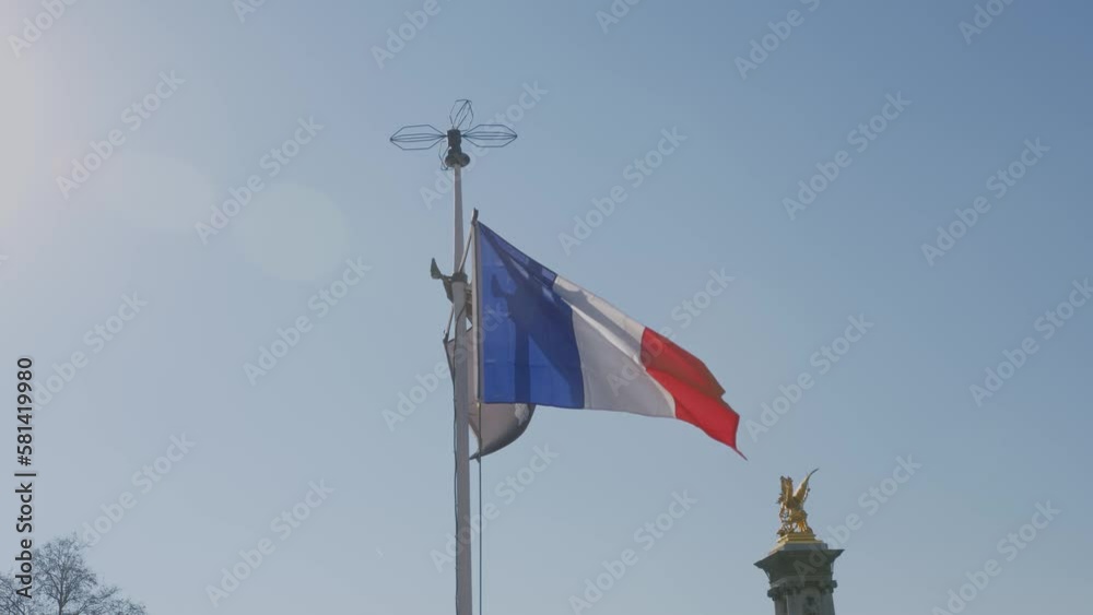 Paris flag wave against blue sky with golden statue of Alexandre bridge in background Paris flag wave against blue sky with golden statue of Alexandre bridge in background
