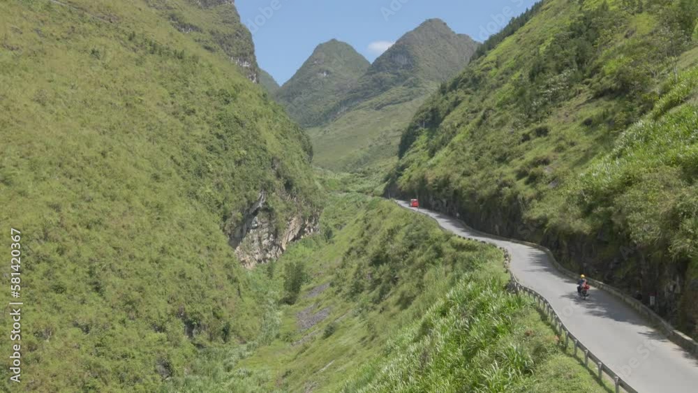 Drone follow up a motobike on mountain path toward two green mountain peaks in Ha Giang Viet Nam Drone follow up a motobike on mountain path toward two green mountain peaks in Ha Giang Viet Nam