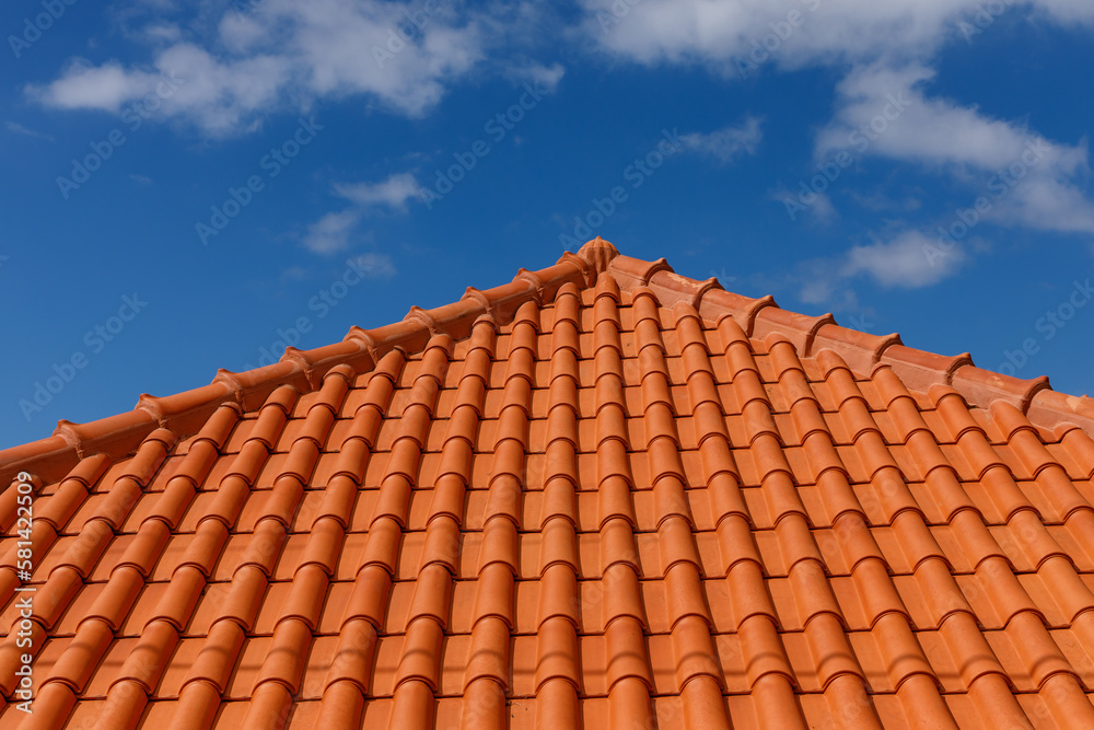 Red tiles panels roof under blue sky.