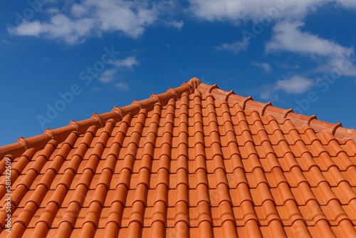 Red tiles panels roof under blue sky. © 9parusnikov