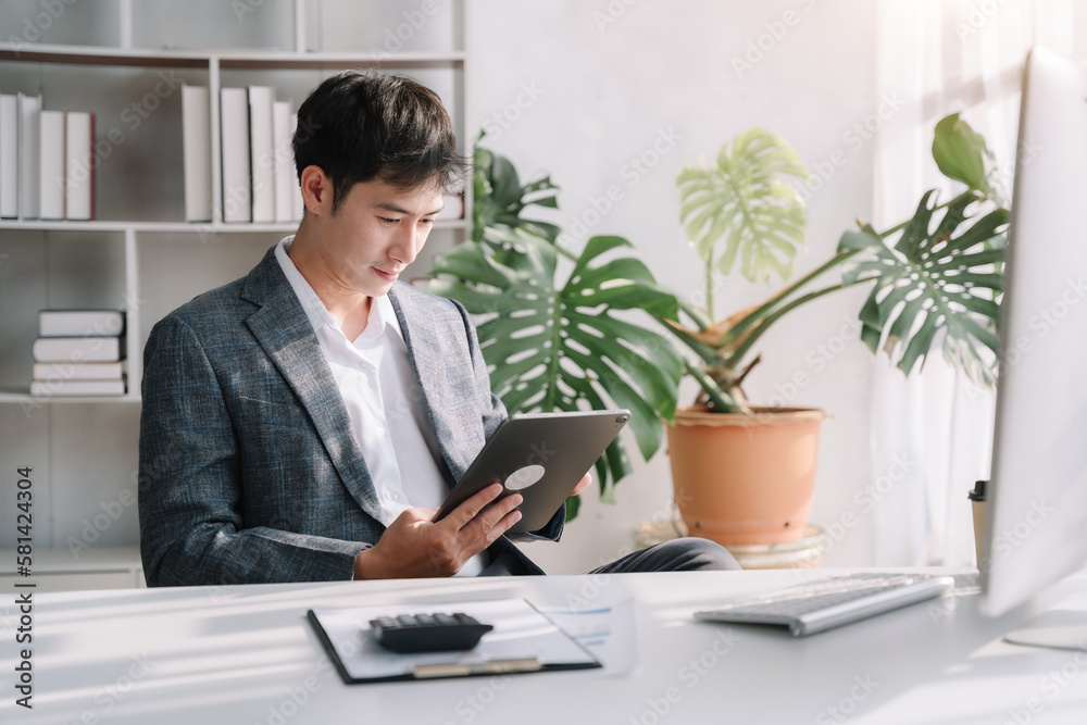 Businessman using a tablet to analysis graph company financial in office.