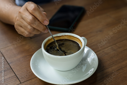 Woman hand and hot coffee in the white cup on wooden table background.Cafe drinking menu black coffee at the restaurant with copy space.