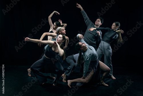 Artistic boys and girls. Group of young people dancing against black studio background. Concept of modern freestyle dance, contemporary art, movements, hobby and creative lifestyle
