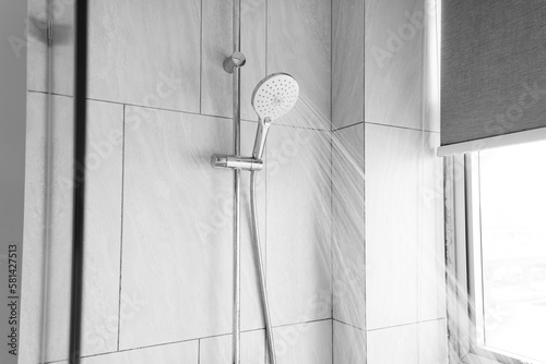 Close up shower head in modern bathroom with water drops flowing.Sanitary ware for bathroom interior.Running water of shower faucet.Fresh shower behind wet glass window with water drops splashing.