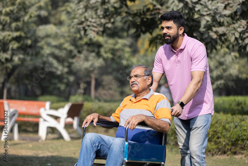 Young man assisting a senior man in a wheelchair at park