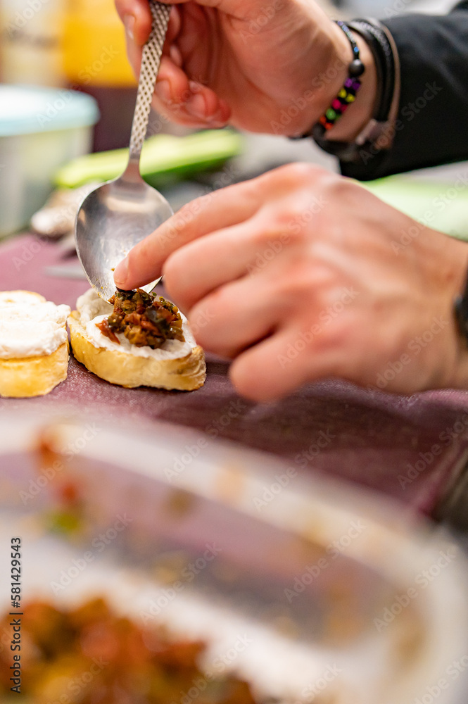 man chef hand cooking tapas with tapenade and cream cheese on restaurant kitchen