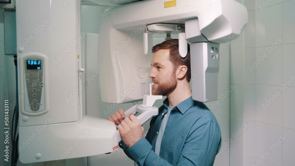Young male patient undergoing panoramic X-ray investigation of oral cavity using an orthopantomographic machine