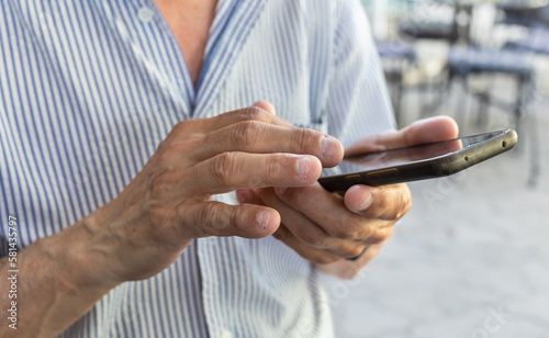 Elderly man is holding a mobile phone in his hands