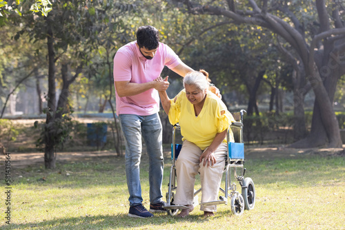 Photography Male physical therapist discussing with senior woman in wheelchair at park