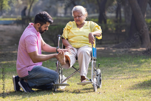 Photography Male physical therapist discussing with senior woman in wheelchair at park