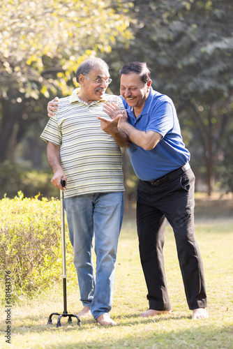 Two happy senior male friends spending leisure time at park