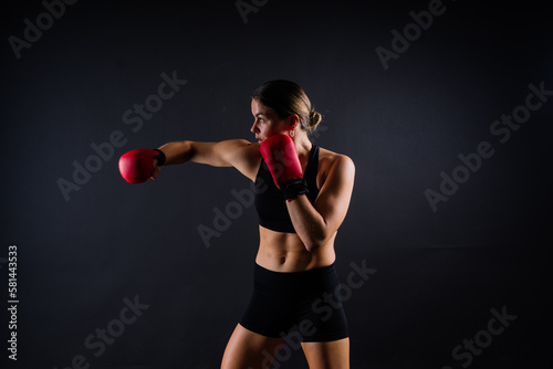 Strong sportswoman in boxing gloves prepared high kick. Isolated on white, red, yellow background © Ivan Zelenin