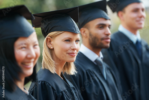 Facing their future. Young college graduates holding their diplomas while standing in a row and smiling.