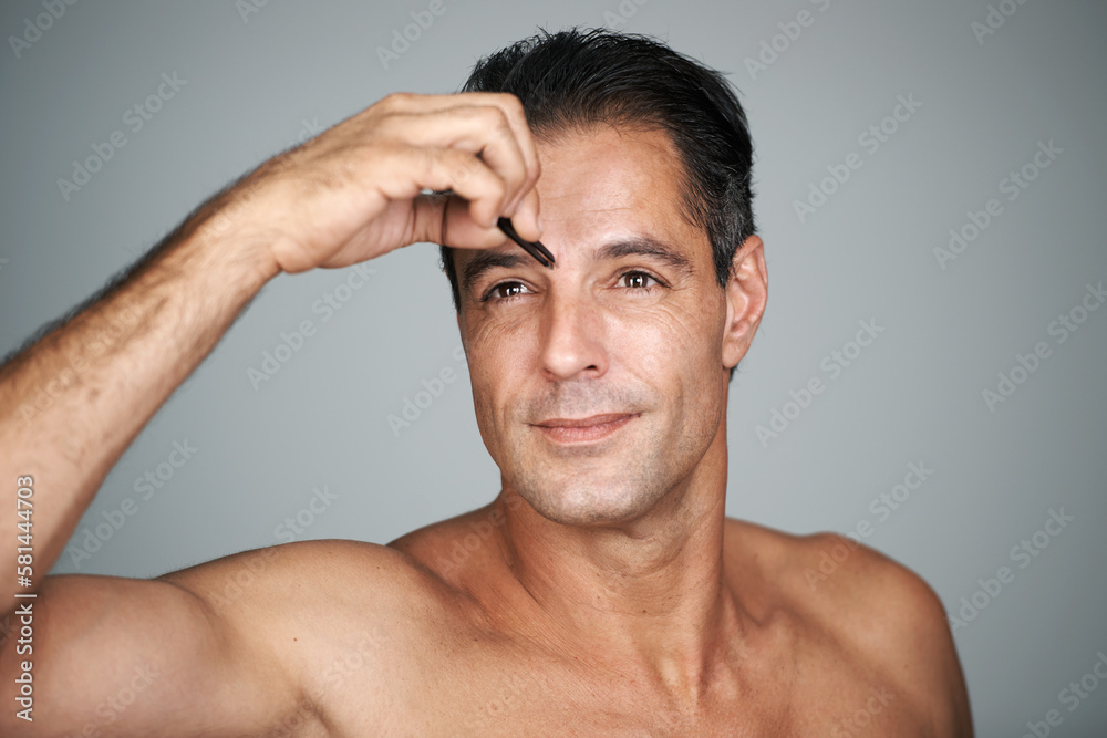 Obraz premium Trimming unwanted hair. Studio shot of a handsome mature man trimming his eyebrows with tweezers.