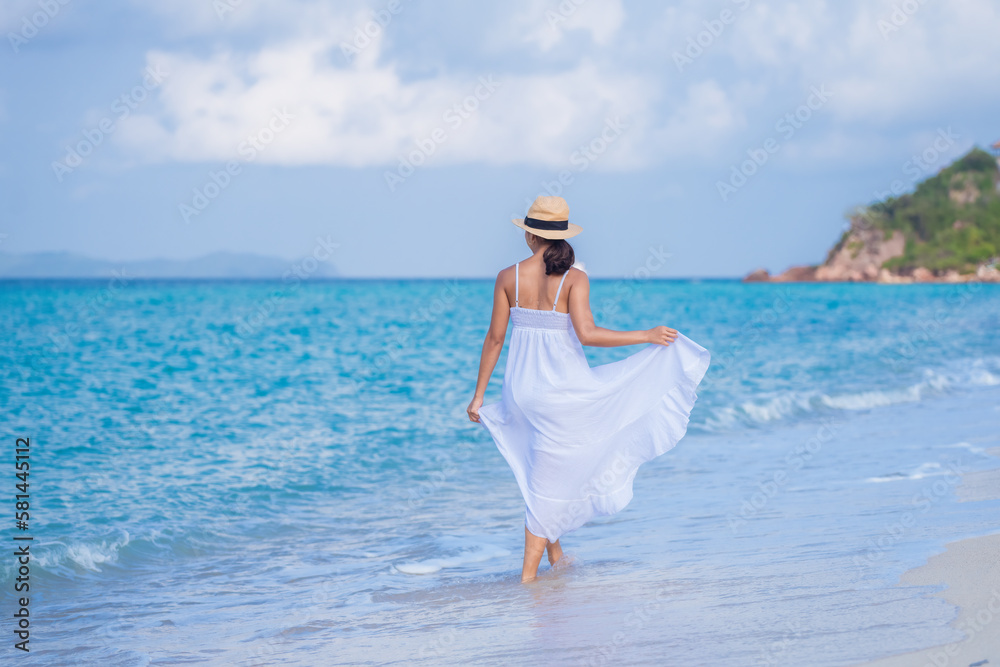 Happy sexy asain traveller woman in white beach dress and hat show enjoys on tropical beach vacation in summer holidays Happy sexy asain traveller woman in white beach dress and hat show enjoys on tropical beach vacation in summer holidays