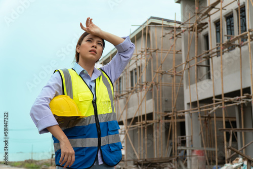 Tired female engineer wiping sweat on face