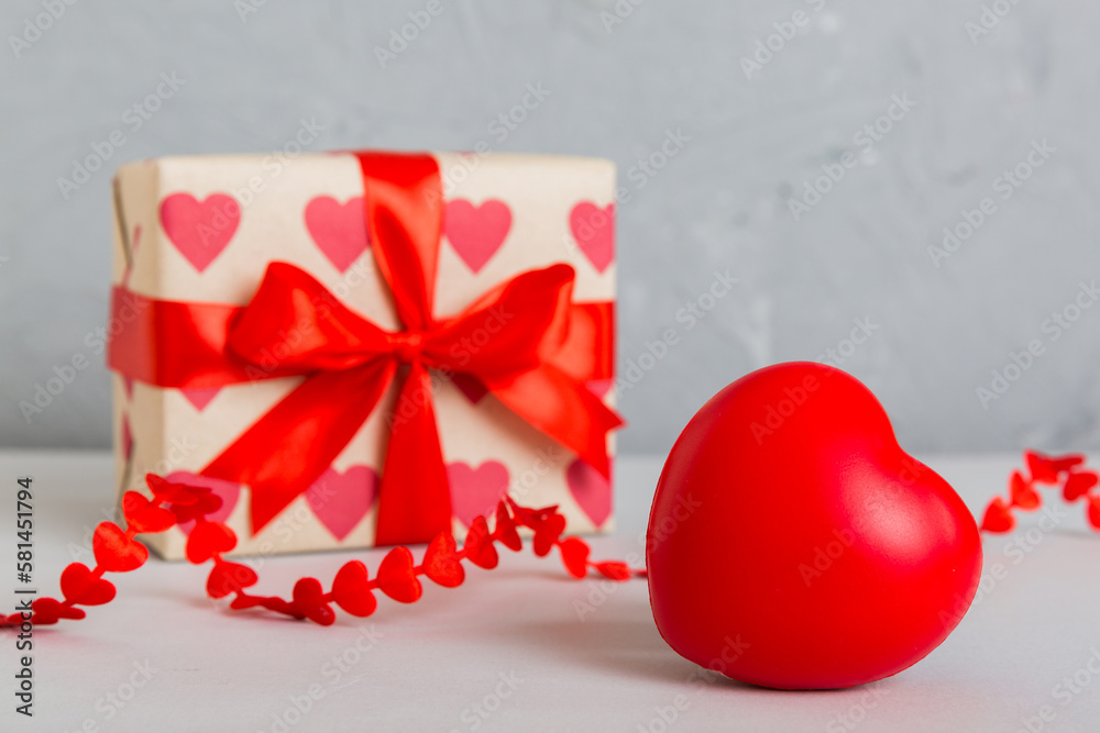 gift box with red bow and red heart on colored background. Perspective view. Flat lay gift box with red bow and red heart on colored background. Perspective view. Flat lay
