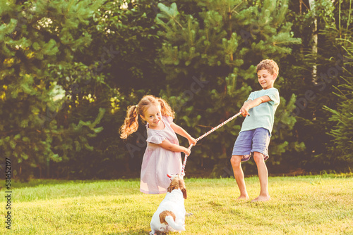 Children playing with their family pet dog tug of war game