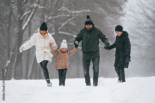 Front view. Happy family is outdoors, enjoying snow time at winter together