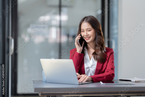 Beautiful Asian businesswoman using a smartphone to view social media applications, answer customer chats, transact through applications online job in an office.