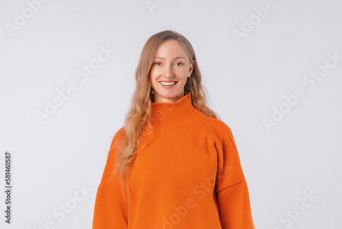 Portrait of attractive cute cheerful girl wearing soft orange sweater, standing over neutral background © AstiMak