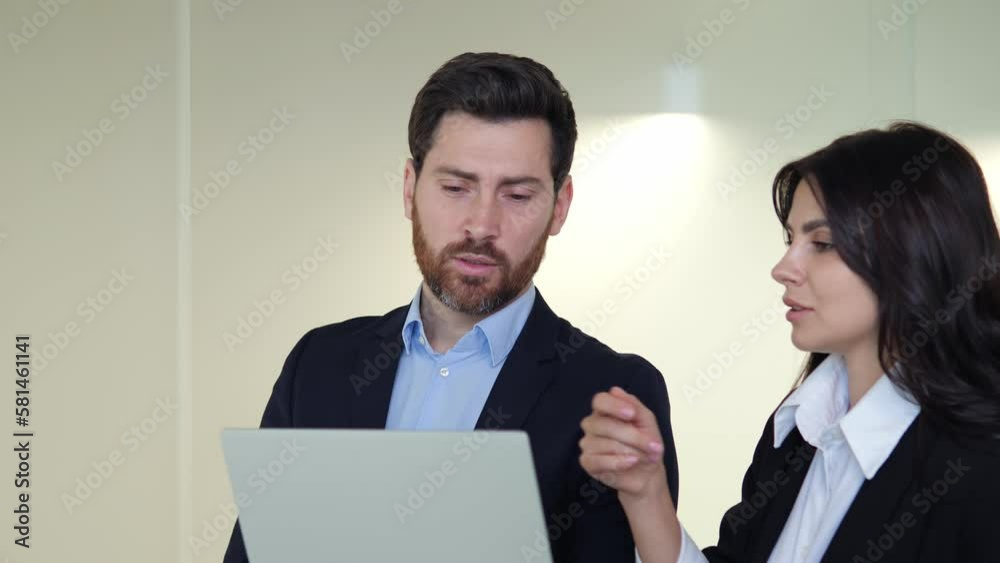 Male and female businessman discussing a project in the office corridor with a laptop, focusing on additional investments and banking systems. Teamwork collaboration in the modern business world. Male and female businessman discussing a project in the office corridor with a laptop, focusing on additional investments and banking systems. Teamwork collaboration in the modern business world.