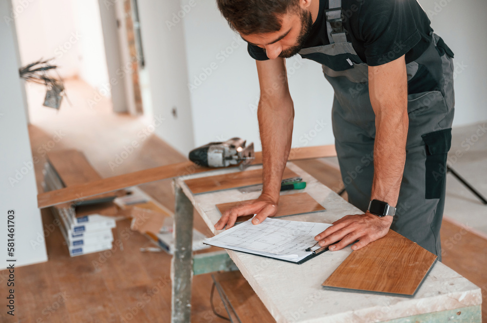 Reading the information. Man is installing new laminated wooden floor Reading the information. Man is installing new laminated wooden floor