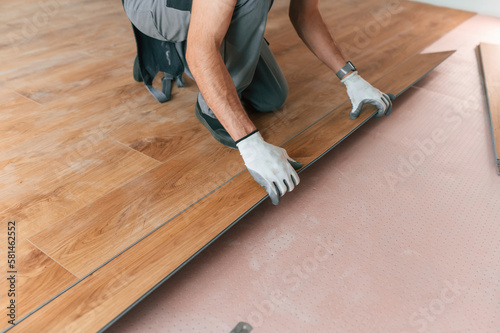 Hand work. Man is installing new laminated wooden floor