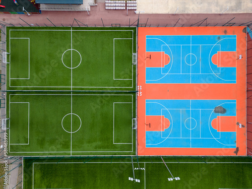 aerial view of a green football field and a colorful basketball court, providing a glimpse of two different sports facilities side by side.