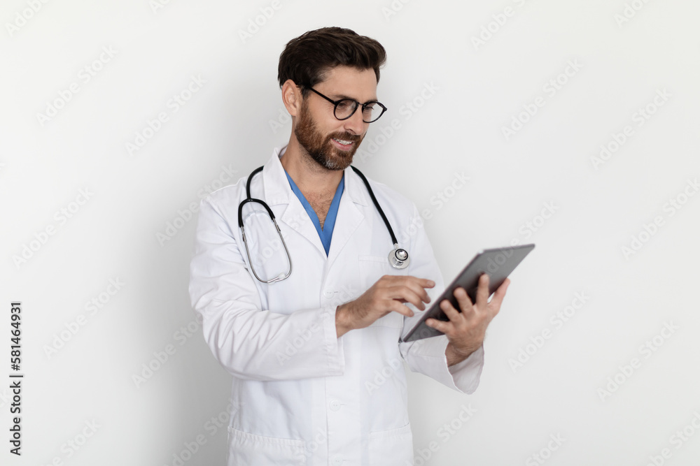 Portrait Of Handsome Male Doctor In Uniform Using Digital Tablet Portrait Of Handsome Male Doctor In Uniform Using Digital Tablet