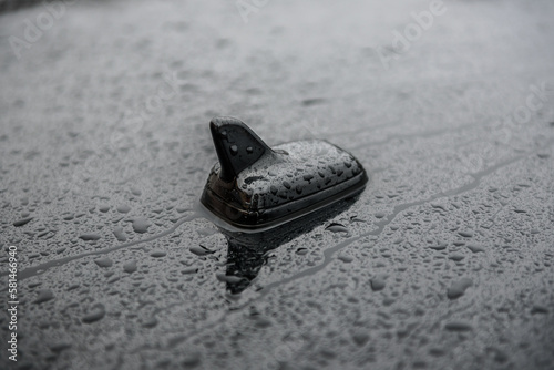GPS antenna on roof of a car for radio navigation system. Antenna on top of black car. Outdoor car radio antenna with drops of water. Details new modern business auto. Closeup.