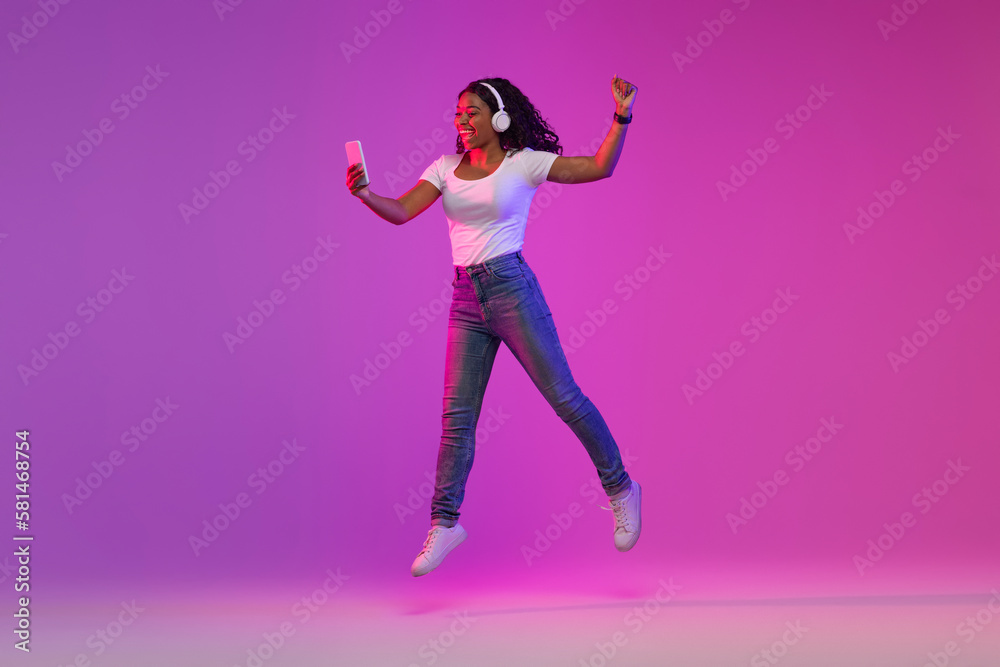 Happy Black Woman With Smartphone In Hand Jumping And Celebrating Success Happy Black Woman With Smartphone In Hand Jumping And Celebrating Success