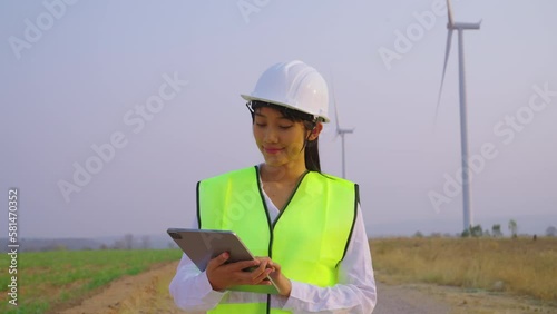 Female engineer checking and survay wind turbine location. She using tablet to check data and work. photo