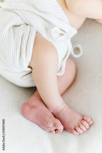 puristische Babyfüße auf weißer Decke mit weißem Höschen
